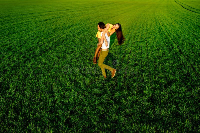 Pares jovenes que se divierten en el campo verde en la primavera o el summ fotografía de archivo Pares jovenes que se divierten en el campo verde en la primavera o el summ fotografía de archivo