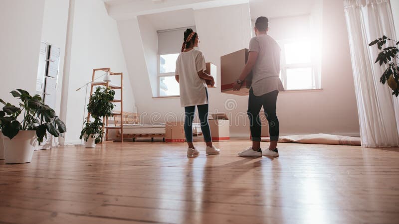 Pares jovenes que se mueven en nueva casa imagen de archivo
