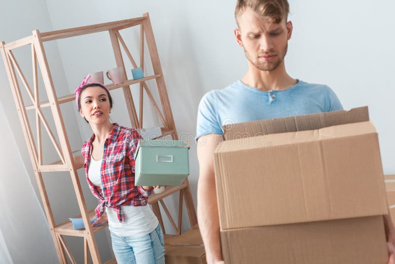 Pares jovenes que se mueven a la nueva situación de la mujer del lugar que pasa el ataúd a la caja que lleva del hombre referida imagen de archivo libre de regalías Pares jovenes que se mueven a la nueva situación de la mujer del lugar que pasa el ataúd a la caja que lleva del hombre referida imagen de archivo libre de regalías