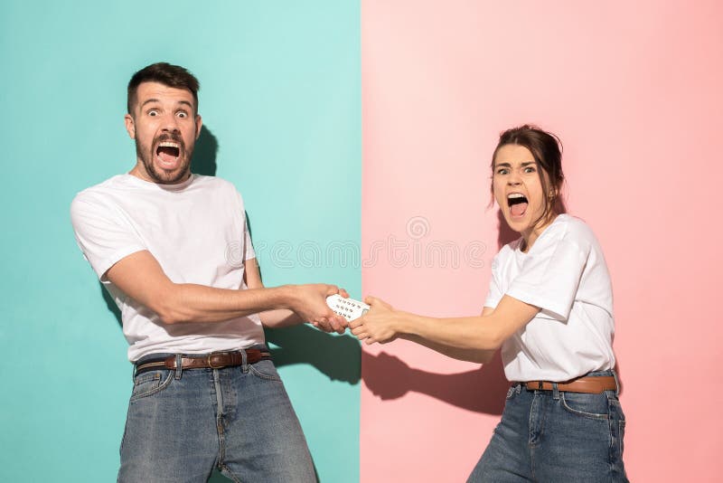 Pares jovenes que ven la TV y que luchan para conseguir el teledirigido fotos de archivo libres de regalías Pares jovenes que ven la TV y que luchan para conseguir el teledirigido fotos de archivo libres de regalías