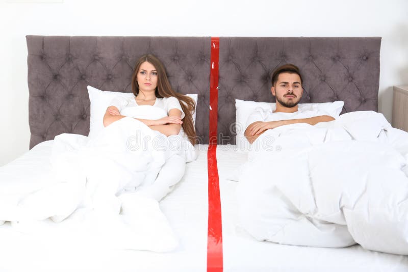 Pares jovenes trastornados con los problemas de la relación que mienten por separado en cama foto de archivo Pares jovenes trastornados con los problemas de la relación que mienten por separado en cama foto de archivo