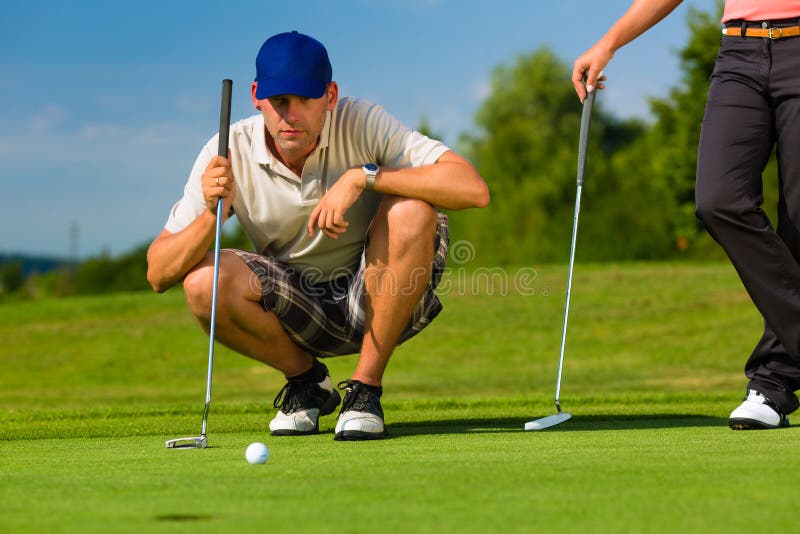 Young golf player on course putting, he aiming for his put shot. Young golf player on course putting, he aiming for his put shot