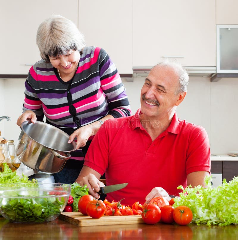 Pares maduros casados felizes que cozinham com tomates imagens de stock royalty free Pares maduros casados felizes que cozinham com tomates imagens de stock royalty free