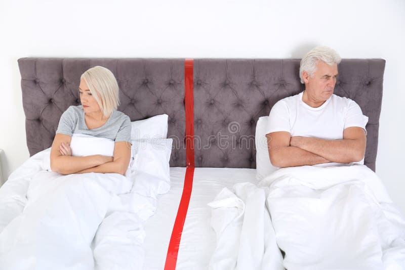 Pares maduros virados com os problemas do relacionamento que encontram-se separadamente na cama imagens de stock Pares maduros virados com os problemas do relacionamento que encontram-se separadamente na cama imagens de stock