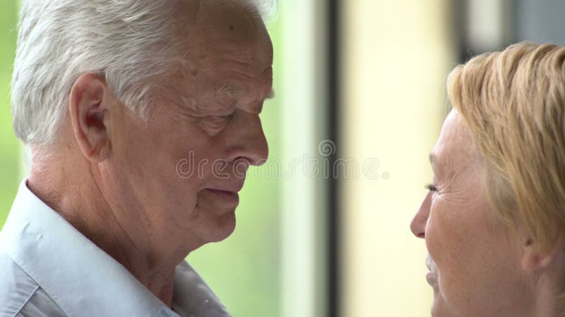 Pares mayores cariñosos y felices en un apartamento moderno hablan y sonríen