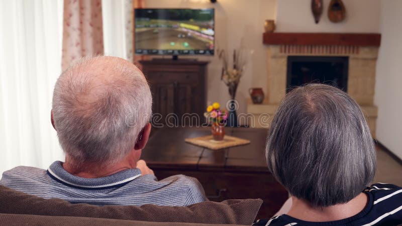 Pares mayores que se sientan junto en la televisión de observación del sofá