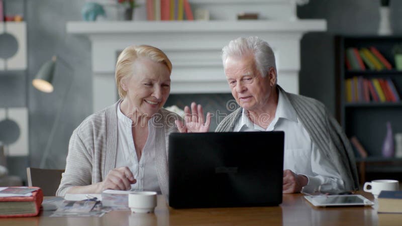 Pares mayores websurfing en Internet con el ordenador portátil Hombre y mujer mayores felices que usa el ordenador