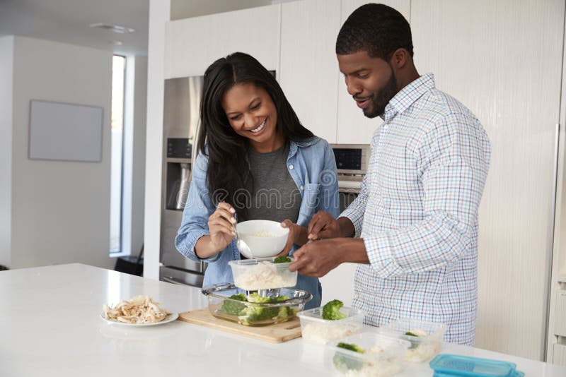 Couple In Kitchen Preparing High Protein Meal And Putting Portions Into Plastic Containers. Couple In Kitchen Preparing High Protein Meal And Putting Portions Into Plastic Containers
