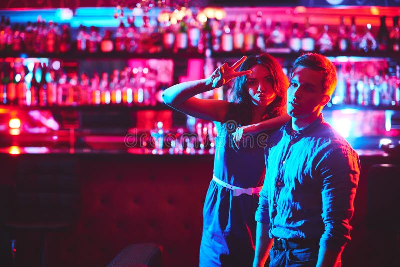 Young couple looking at camera in bar of night club. Young couple looking at camera in bar of night club