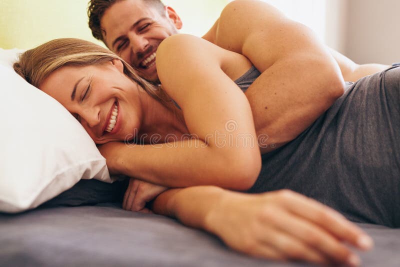 Pares novos bonitos no amor que encontra-se na cama foto de stock Pares novos bonitos no amor que encontra-se na cama foto de stock