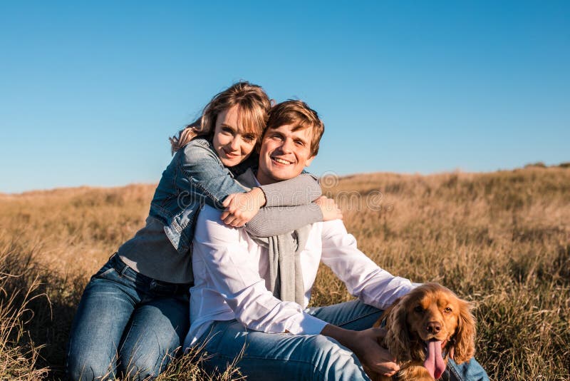 Pares novos felizes que abraçam e que riem fora imagem de stock Pares novos felizes que abraçam e que riem fora imagem de stock