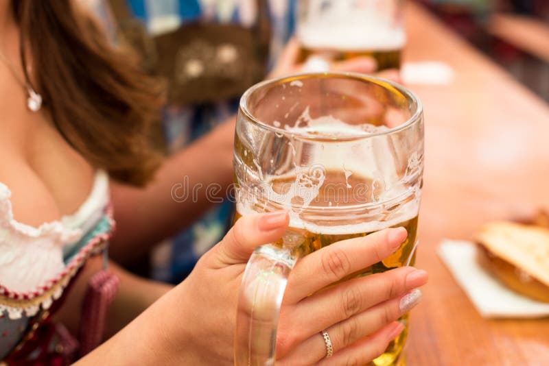 Pares novos que brindam na barraca da cerveja de Oktoberfest foto de stock royalty free Pares novos que brindam na barraca da cerveja de Oktoberfest foto de stock royalty free