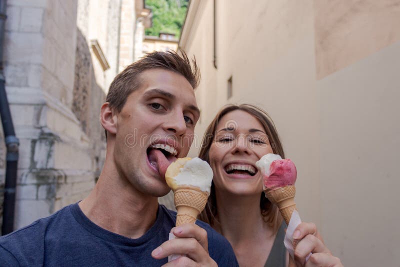 Pares novos que comem o gelado em uma aleia imagem de stock Pares novos que comem o gelado em uma aleia imagem de stock