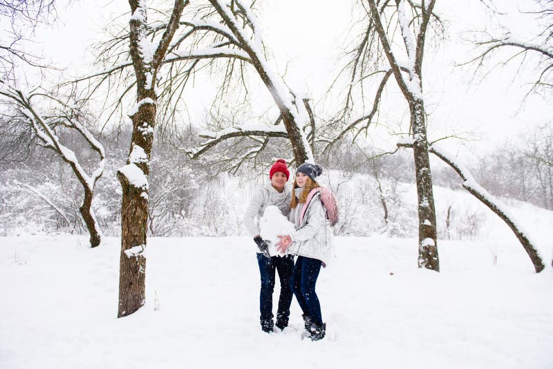 Pares novos que guardam a bola da neve fotos de stock Pares novos que guardam a bola da neve fotos de stock