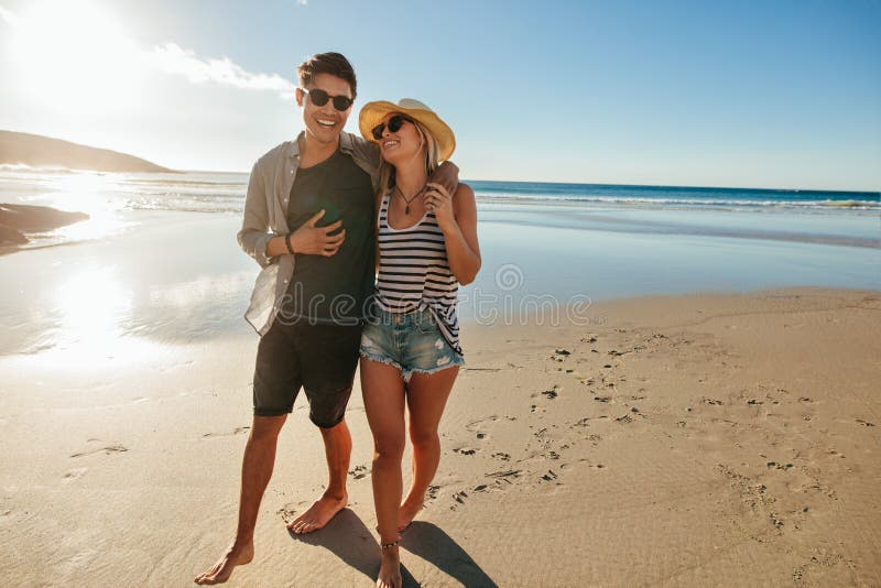 Pares novos românticos que andam na praia imagens de stock Pares novos românticos que andam na praia imagens de stock