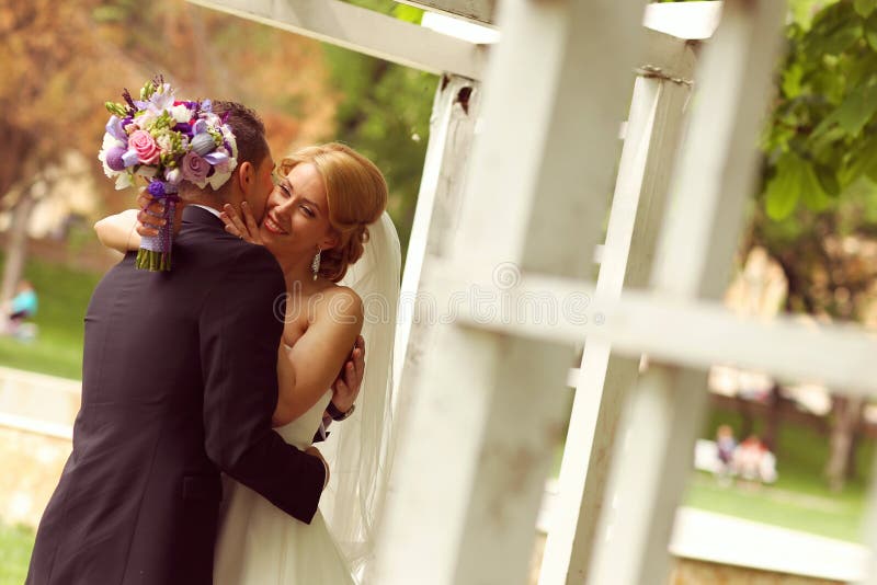 Pares nupciales hermosos que se divierten en el parque en su ramo de la flor del día de boda imagen de archivo libre de regalías