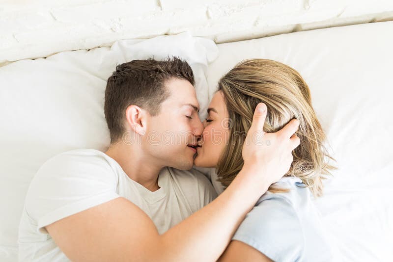 Pares que beijam ao encontrar-se na cama imagem de stock Pares que beijam ao encontrar-se na cama imagem de stock