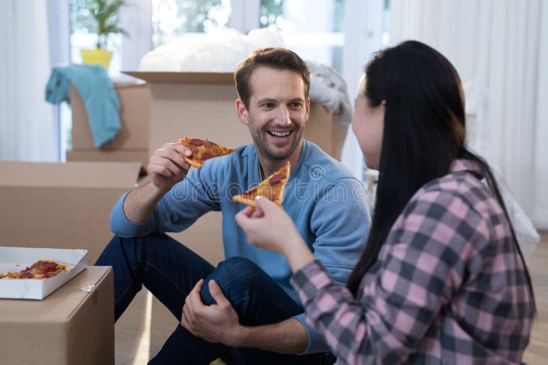 Pares que comen pizza en su nuevo hogar imágenes de archivo libres de regalías