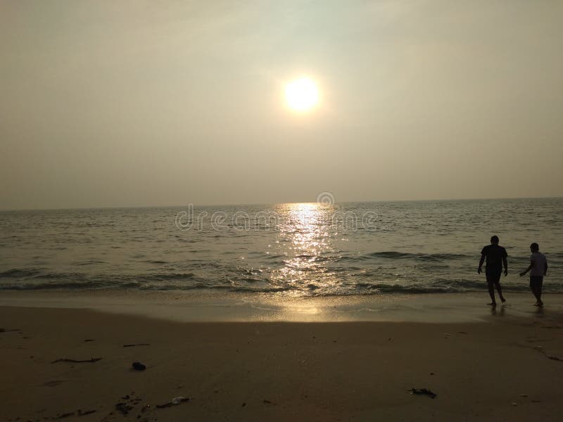 Pares que disfrutan de la bonita vista del calmsea de la puesta del sol que se relaja imagen de archivo libre de regalías Pares que disfrutan de la bonita vista del calmsea de la puesta del sol que se relaja imagen de archivo libre de regalías