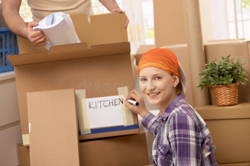 Man packing kitchen equipment into box, girlfriend signing box, smiling. Man packing kitchen equipment into box, girlfriend signing box, smiling.