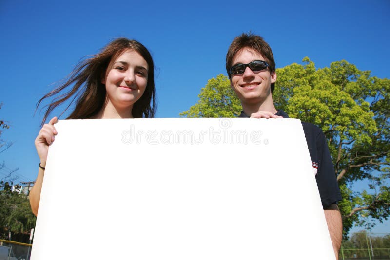 Pares que prendem um sinal em branco foto de stock Pares que prendem um sinal em branco foto de stock