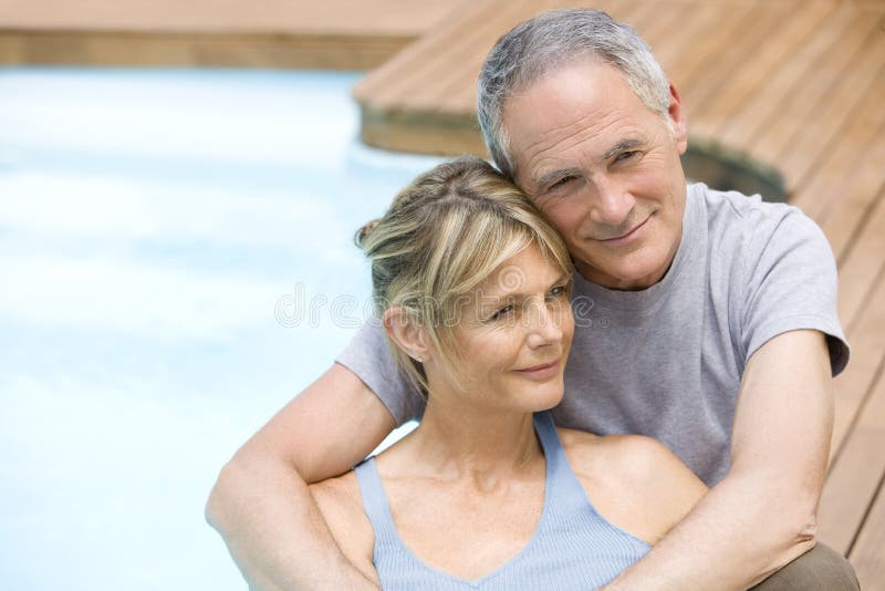 Pares que relaxam pela piscina foto de stock Pares que relaxam pela piscina foto de stock