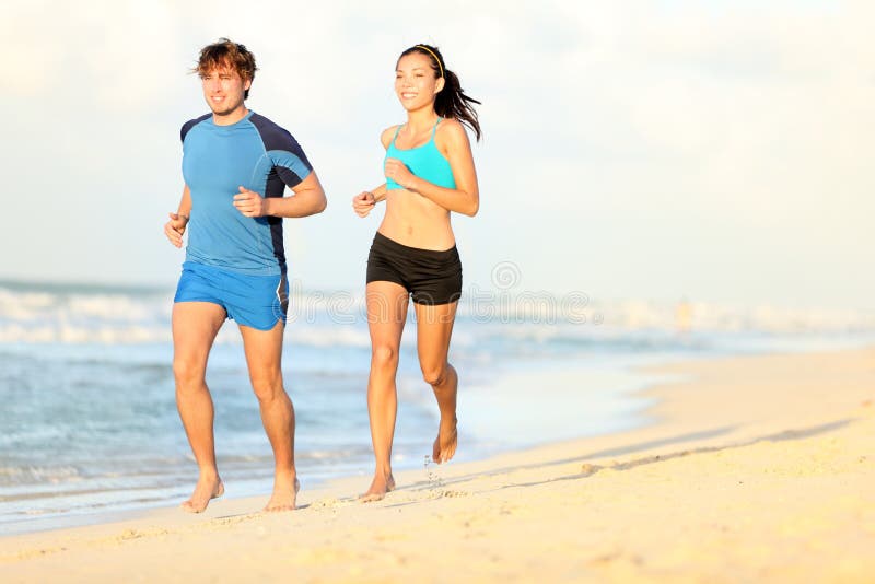 Pares que se ejecutan en la playa imagen de archivo libre de regalías Pares que se ejecutan en la playa imagen de archivo libre de regalías