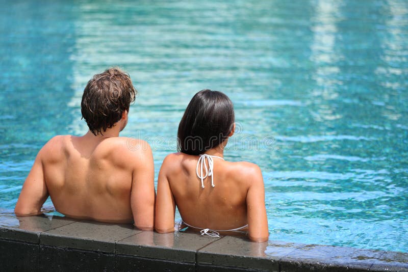 Pares que se relajan en centro turístico de la piscina del infinito imagen de archivo libre de regalías Pares que se relajan en centro turístico de la piscina del infinito imagen de archivo libre de regalías