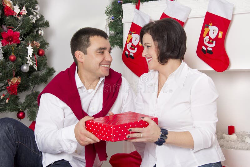Pares que se sientan cerca de la chimenea de la Navidad imagen de archivo libre de regalías Pares que se sientan cerca de la chimenea de la Navidad imagen de archivo libre de regalías