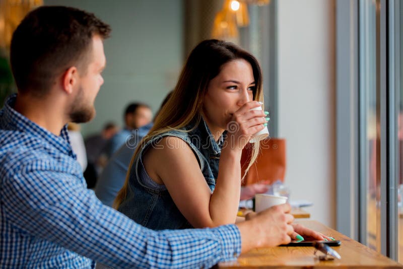 Pares que se sientan en una tabla en un café y un café de consumición imágenes de archivo libres de regalías Pares que se sientan en una tabla en un café y un café de consumición imágenes de archivo libres de regalías