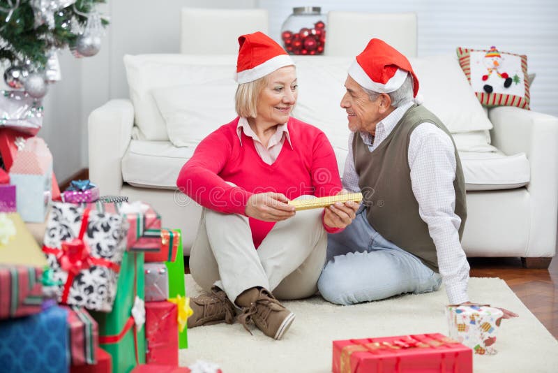 Pares que vestem Santa Hats Looking At Each outro fotos de stock Pares que vestem Santa Hats Looking At Each outro fotos de stock