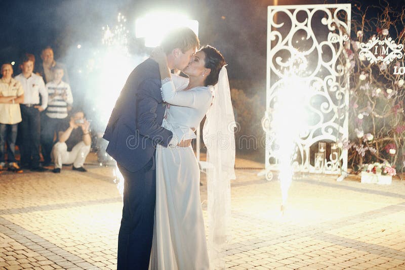 Pares románticos felices que se besan en la recepción, fuegos artificiales b del recién casado imágenes de archivo libres de regalías Pares románticos felices que se besan en la recepción, fuegos artificiales b del recién casado imágenes de archivo libres de regalías