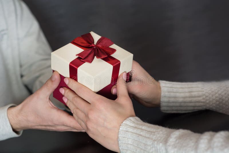 Pares románticos jovenes que se sientan en la tabla y el hombre del restaurante que dan la caja de regalo a las manos femeninas j foto de archivo libre de regalías Pares románticos jovenes que se sientan en la tabla y el hombre del restaurante que dan la caja de regalo a las manos femeninas j foto de archivo libre de regalías
