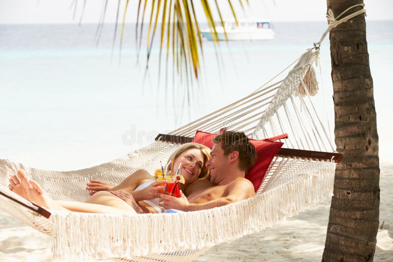 Pares románticos que se relajan en hamaca de la playa imagen de archivo Pares románticos que se relajan en hamaca de la playa imagen de archivo
