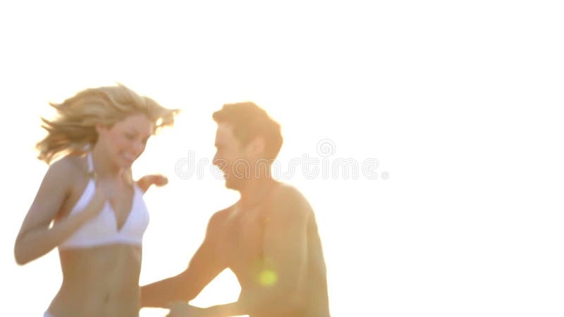 Pares românticos que correm na praia tropical bonita
