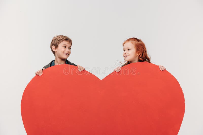 pares sonrientes de los niños detrás del corazón rojo grande imagenes de archivo pares sonrientes de los niños detrás del corazón rojo grande imagenes de archivo