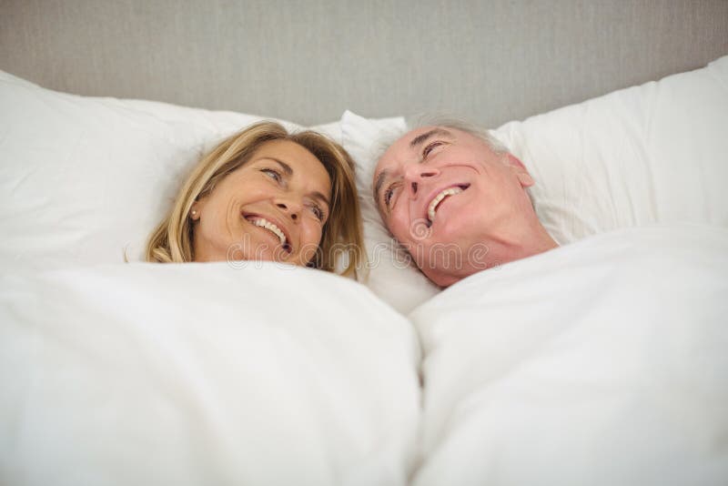 Pares superiores felizes que encontram-se na cama fotografia de stock Pares superiores felizes que encontram-se na cama fotografia de stock