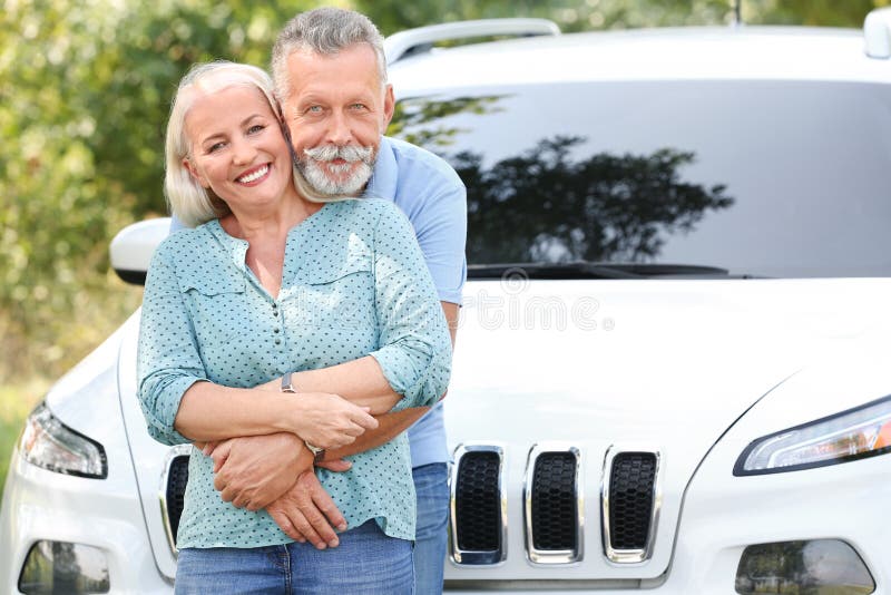 Pares superiores felizes que levantam perto do carro imagens de stock royalty free Pares superiores felizes que levantam perto do carro imagens de stock royalty free
