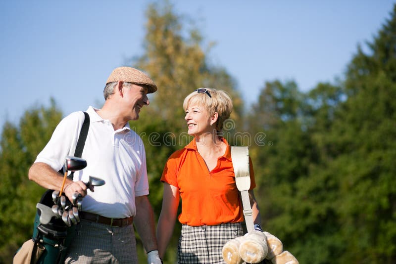 Pares sênior que jogam o golfe imagem de stock Pares sênior que jogam o golfe imagem de stock
