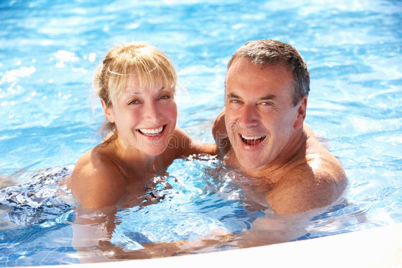 Pares sênior que têm o divertimento na piscina imagem de stock Pares sênior que têm o divertimento na piscina imagem de stock