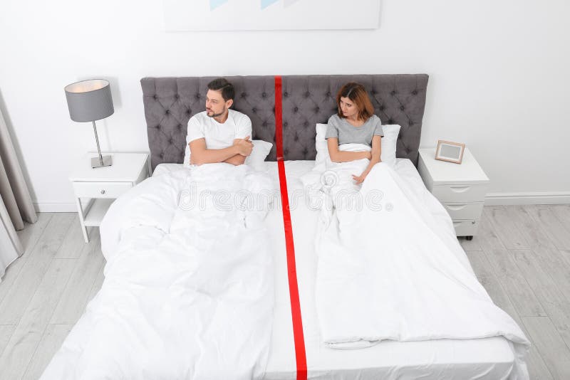 Pares trastornados con los problemas de la relación que mienten por separado en cama fotografía de archivo libre de regalías Pares trastornados con los problemas de la relación que mienten por separado en cama fotografía de archivo libre de regalías