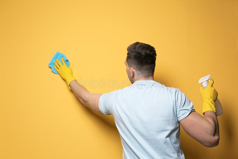 Parete di pulizia dell'uomo con lo straccio e lo spruzzatore fotografie stock Parete di pulizia dell'uomo con lo straccio e lo spruzzatore fotografie stock