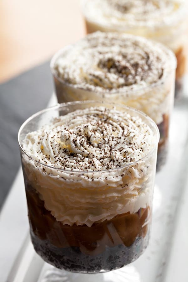 Banana caramel parfait desserts with fresh whipped cream and chocolate cookie crumbles. Shallow depth of field. Banana caramel parfait desserts with fresh whipped cream and chocolate cookie crumbles. Shallow depth of field.