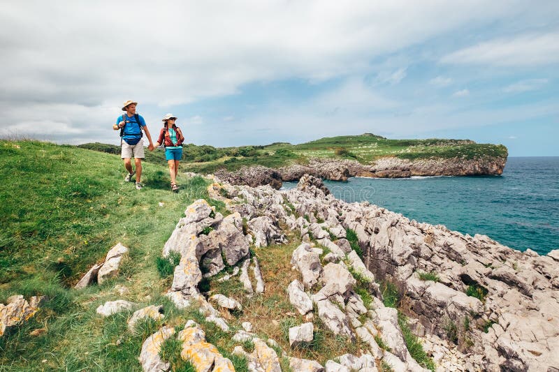 Parfotvandrarehandelsresande går på stenig kust för havet royaltyfri foto Parfotvandrarehandelsresande går på stenig kust för havet royaltyfri foto