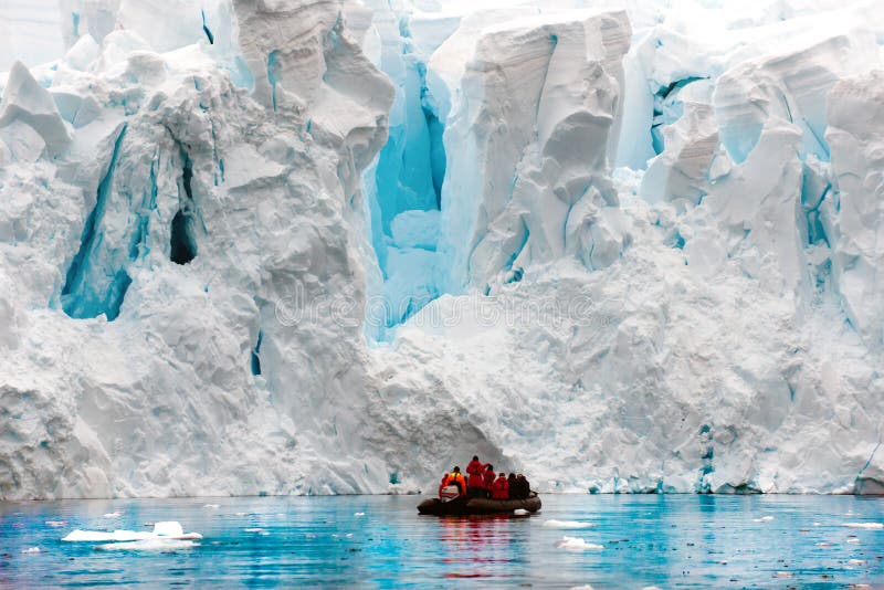 Parida del glaciar en el antártico, gente en zodiaco delante de la escarpa del glaciar