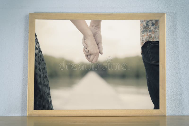 Parinnehavhänder i bildramen som förläggas på den wood tabellen arkivfoto Parinnehavhänder i bildramen som förläggas på den wood tabellen arkivfoto