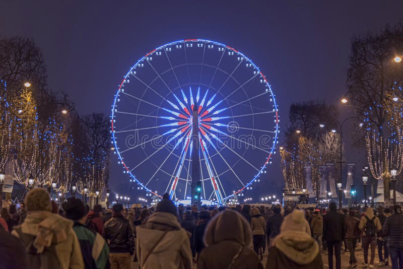 Nový rok oslava dav chůze od Champs Elysées, aby se Concorde místo a Ruské kolo v noci, Paříž, Francie.