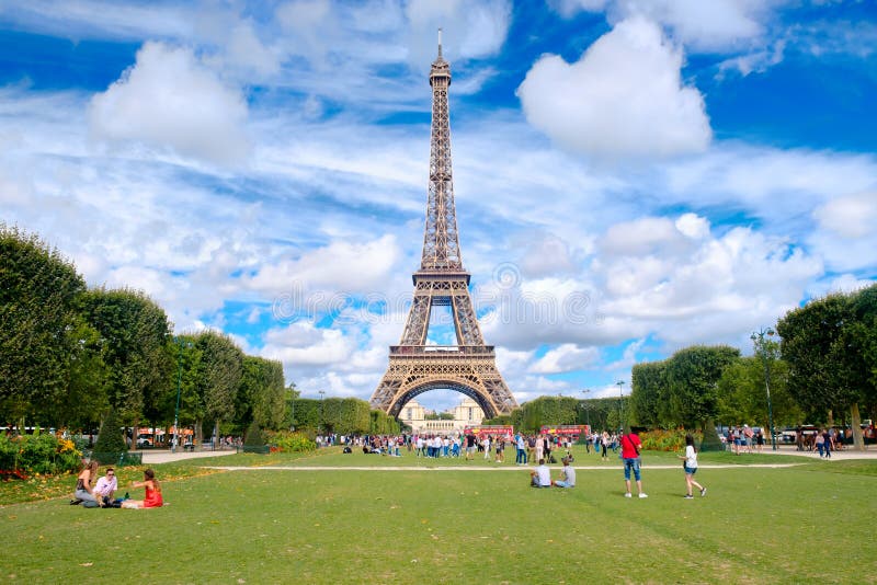 PARIS,FRANCE - JULY 30,2017 : The Eiffel Tower and tourists at the Champ de Mars on a beautiful summer day in Paris. PARIS,FRANCE - JULY 30,2017 : The Eiffel Tower and tourists at the Champ de Mars on a beautiful summer day in Paris