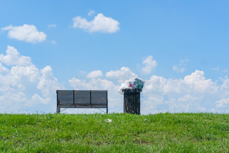 Park Bench and Overflowing Trash Can royalty free stock image