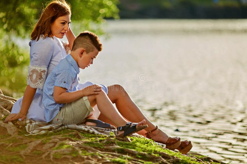 Parkerar matar den gravida modern för barn som går med hennes lilla son i sommar, nära sjön och änderna arkivfoto Parkerar matar den gravida modern för barn som går med hennes lilla son i sommar, nära sjön och änderna arkivfoto